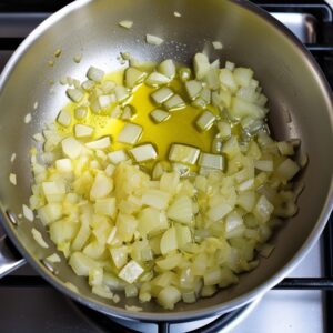 Finely chopped onions sautéing in olive oil in a saucepan over medium heat, turning soft and translucent as they cook.